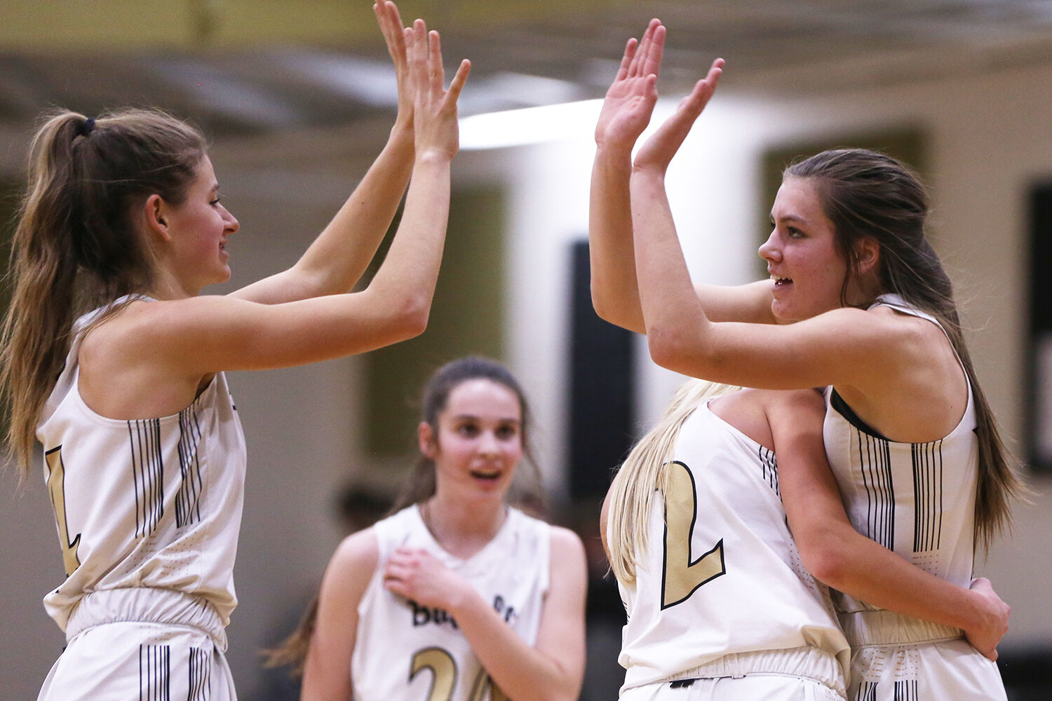 Kendall Tietjen hugs freshman Tess Rule while she high fives Lexi Rule